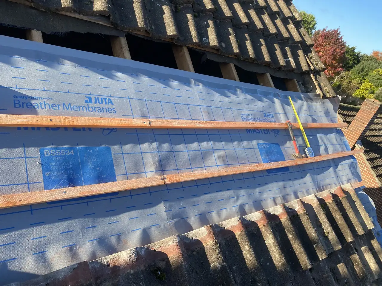 New breathable roof membrane and timber battens on a roof being re-tiled