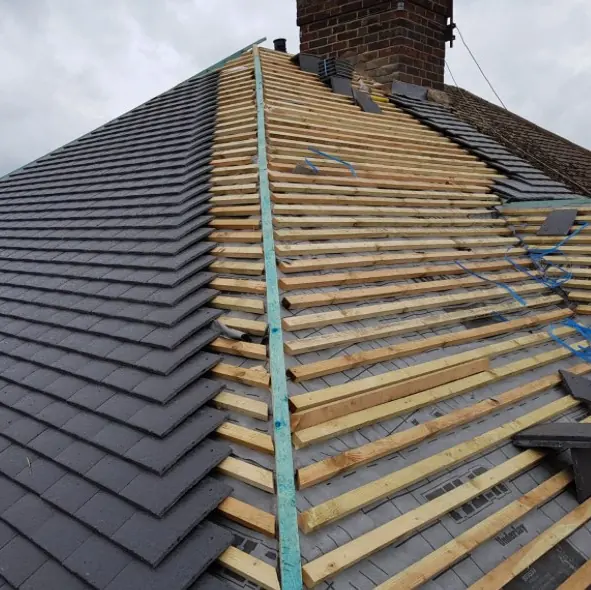 Roof half way through re-tiling, new grey tiles on one side and new battens on the other