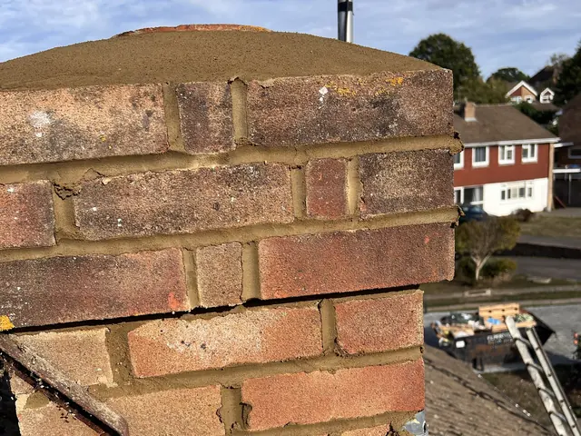 Chimney stack with freshly repointed brickwork and a new mortar top, above a tiled roof